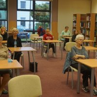 Zdjęcie zebranych gości, widać 9 osób siedzących przy stolikach.