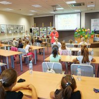 Panie bibliotekarki z oddziału dla dzieci rozpoczynają spotkanie, zebrane dzieci siedzą przy stołach.