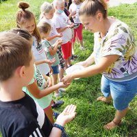 Pani bibliotekarka rozdaje dzieciom nasiona kwietnej łąki.