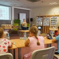 Pani bibliotekarka tłumaczy dzieciom budowę domku i wyjaśnia jakie owady chętniej skorzystają z danego rodzaju wypełnienia.