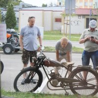 Trzech mężczyzn oglądających zabytkowy motocykl.