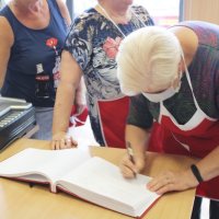 Panie z koła gospodyń wiejskich wpisują się do księgi pamiątkowej w bibliotece.