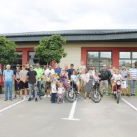 Grupowe zdjęcie uczestników spotkania na parkingu przed biblioteką.