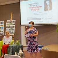 Dyrektor biblioteki Grażyna Szafraniak wita zebranych uczestników, pani Małgorzata Jarocińska czeka, siedząc na fotelu.