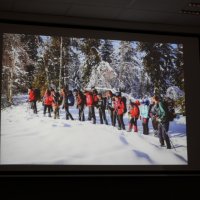 Zdjęcie z prezentacji pana Leszka Szczasnego pokazujące zimowy krajobraz i idącą grupę ludzi. 