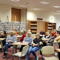 Zajęcie publiczności, widać na nim osoby siedzące na krzesłach i słuchające zaproszonej autorki.