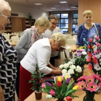 Pani Helena podpisuje się w kronice pamiątkowej, za nią w kolejce czekają uczestnicy spotkania.