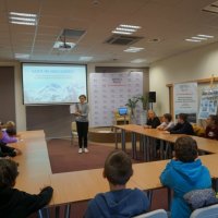 Kolejni uczniowie z innej klasy siedzą przy stołach i biorą udział w lekcji bibliotecznej.