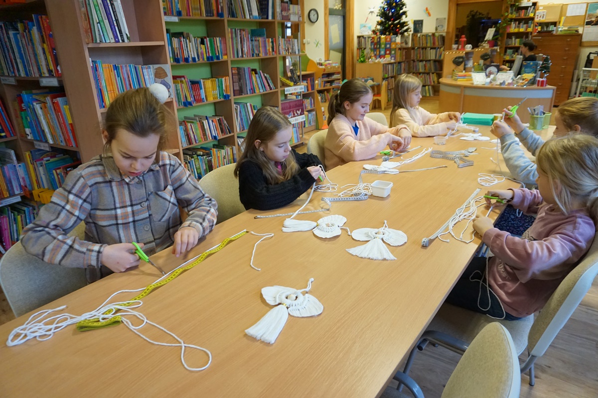 Dzieci pracujące na warsztatach siedzą przy stołach