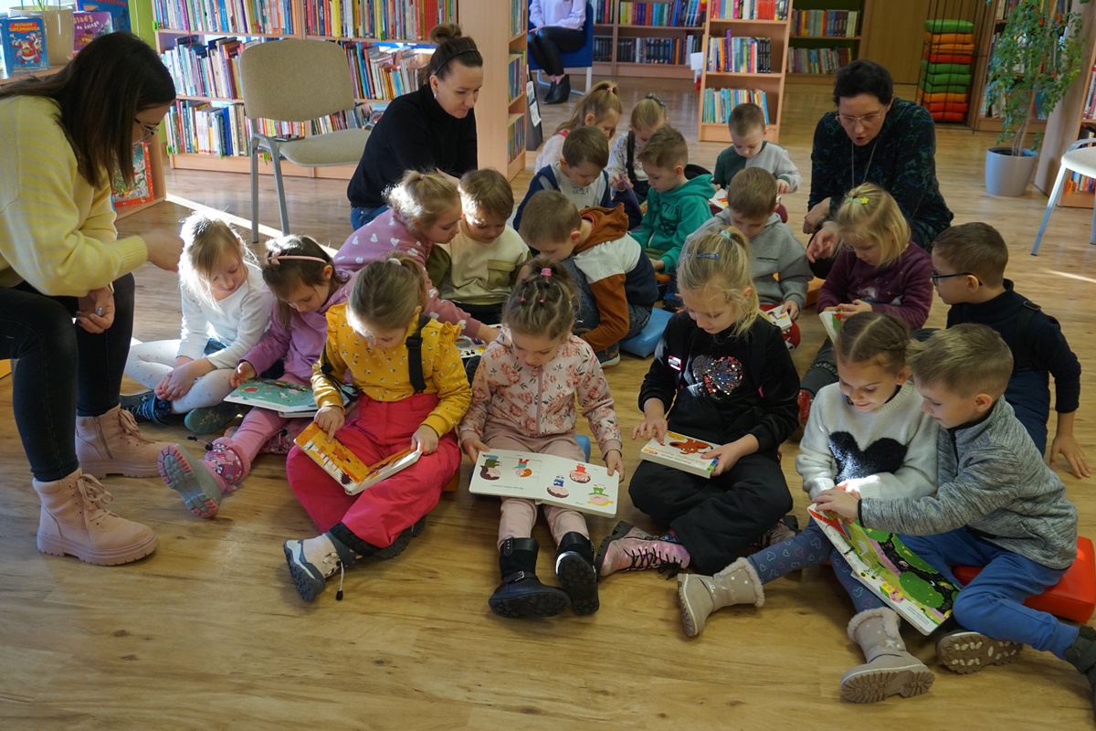 dzieci siedzą z otwartymi na kolanach książkami