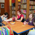 Uczestniczki i prowadząca siedzą przy stole, rozmawiają o przeczytanej książce