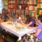 4 dziewczyny i jedna bibliotekarka siedzą wokół stołu i rozmawiają o przeczytanej książce