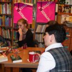 bibliotekarka i dwie uczestniczki spotkania siedzą przy stole na którym leżą książki