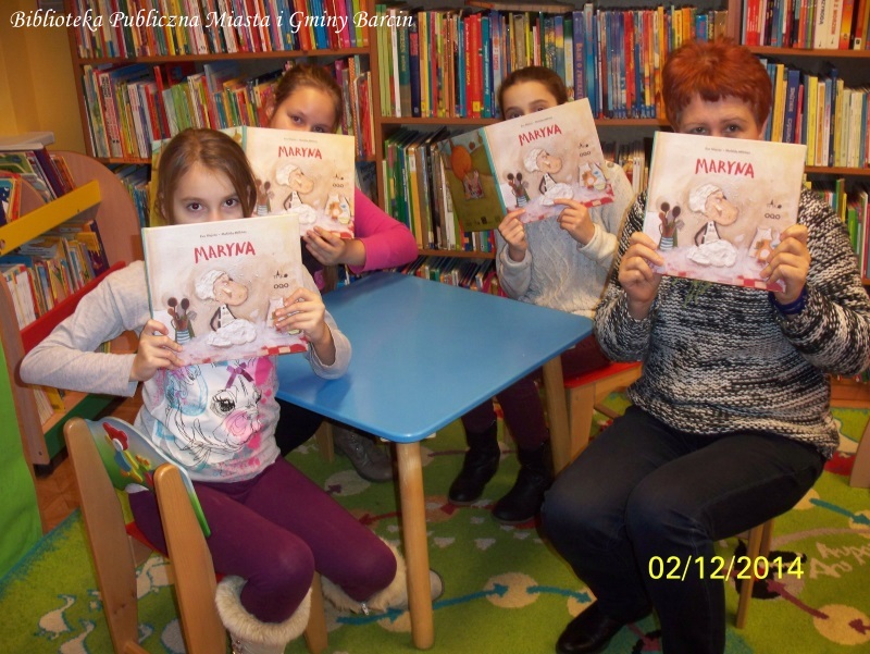 3 dziewczynki i bibliotekarka siedzą przy stoliku, w rękach trzymają książki