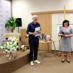 po prawej stronie dyrektorka biblioteki w Barcinie, po lewej zaproszony gość Michał Wójcik, obydwoje sie uśmiechają, pan Michał trzyma w rękach wręczone podziękowania za spotkanie i upominek w formie książki