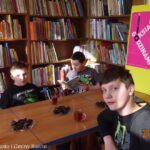 grupa dzieci w czasie spotkania, jeden z chłopców czyta otwartą książkę
