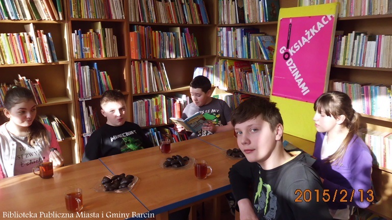 grupa dzieci w czasie spotkania, jeden z chłopców czyta otwartą książkę