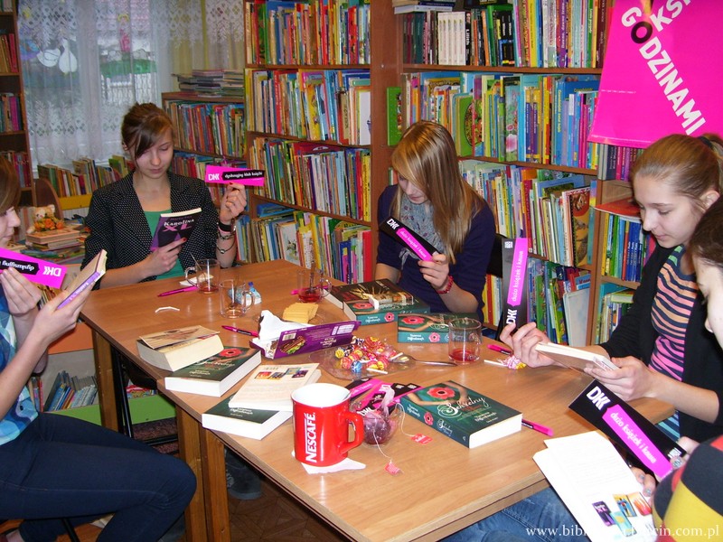 Uczestniczki spotkania siedzą przy stole w rękach trzymają książki i zakładki z logo DKK