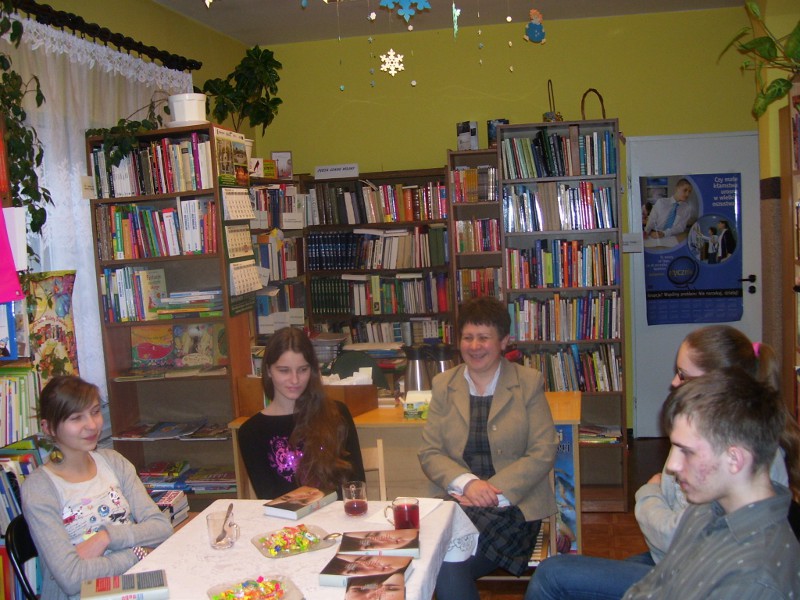 5 osób w czasie spotkania siedzą wokół stołu i rozmawiają o przeczytanej ksiażce