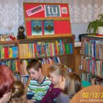 dzieci i prowadząca spotkanie bibliotekarka oglądają książki
