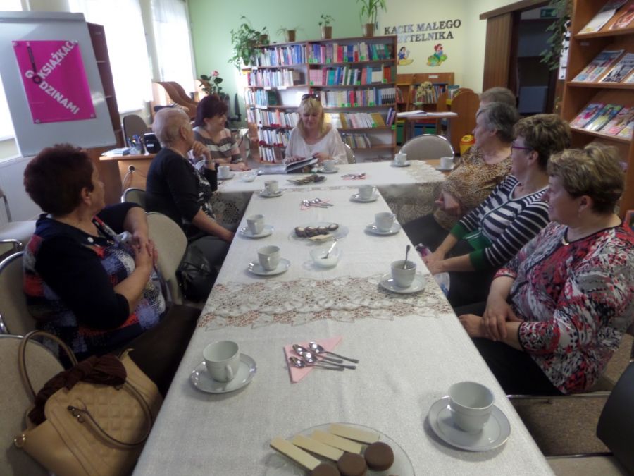 Drugie ujęcie gdzie 8 kobiet siedzi przy stołach ustawionych w literę T i rozmawia między sobą.