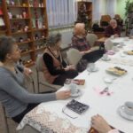 osoby zebrane na spotkaniu DKK siedzą przy stołach i rozmawiają o przeczytanej książce