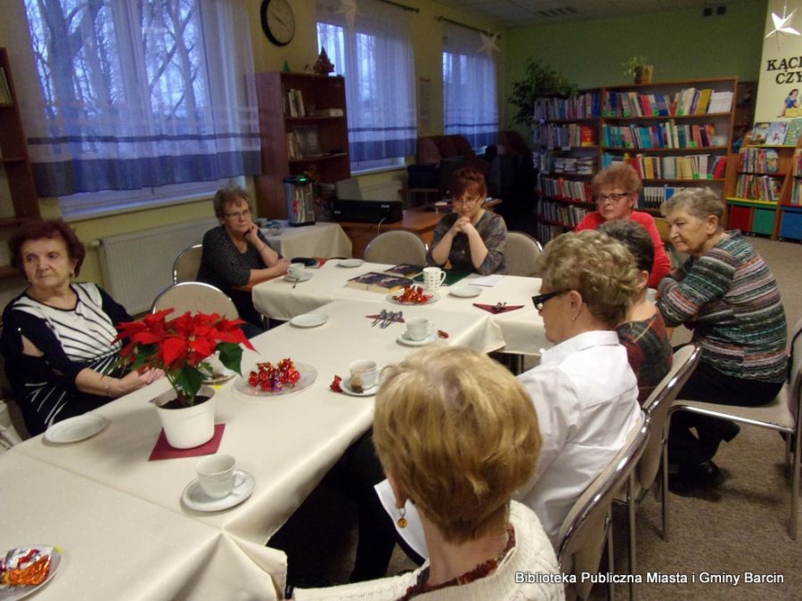 Na zdjęciu widać osiem z dziesięciu osób biorących udział w spotkaniu, wszyscy siedzą przy stołach, na których ustawiono filiżanki do kawy lub herbaty.