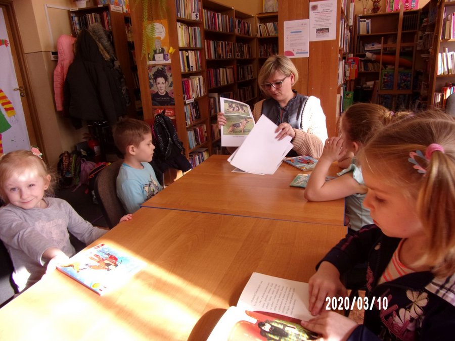 Pani bibliotekarka pokazuje dzieciom ilustracje psów.