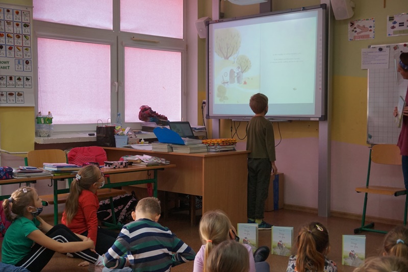 Chłopiec stoi przed ekranem, na którym wyświetlana jest prezentacja.