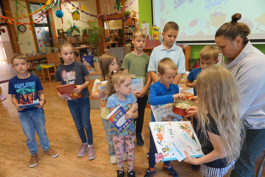 bibliotekarka wręcza lizaki uczestnikom konkursu obecnym na spotkaniu