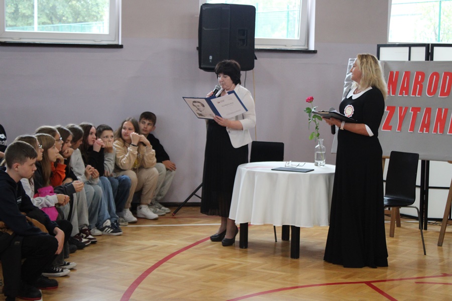 Dyrektorki Biblioteki w Barcinie i Zespołu Szkół w Barcinie stoją przed zebrana publicznością i odczytują coś z trzymanych w rękach teczek