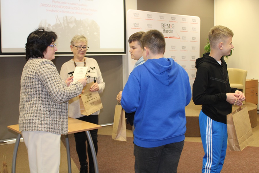 Dyrektorka biblioteki wręcza uczestnikom jednej z drużyn nagrody za udział w wydarzeniu