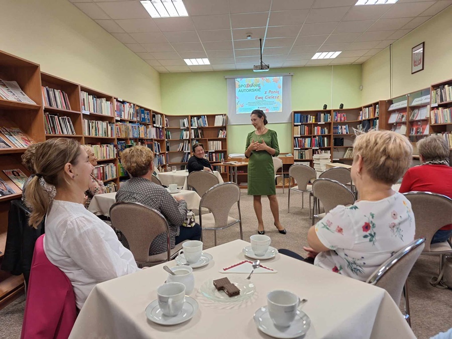 autorka stojąca między publicznością siedzącą przystoliakch